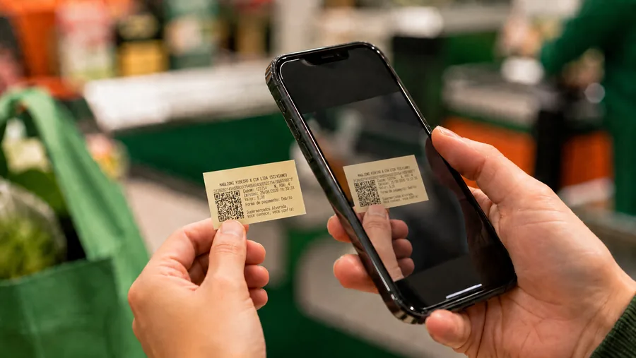 Cliente segurando o cupom reduzido e lendo o QR Code com o celular